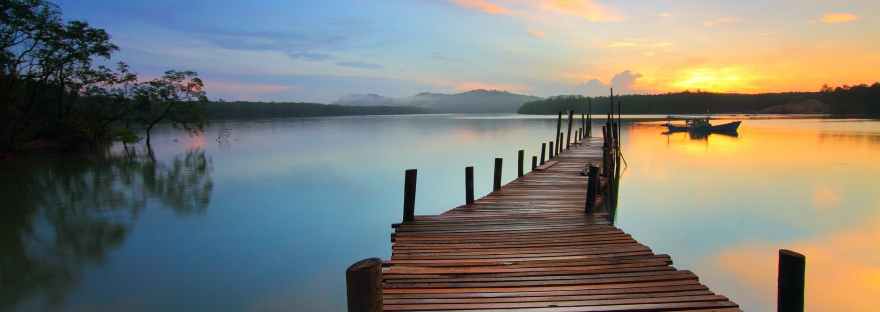 wooden pier stretching across water at sunset